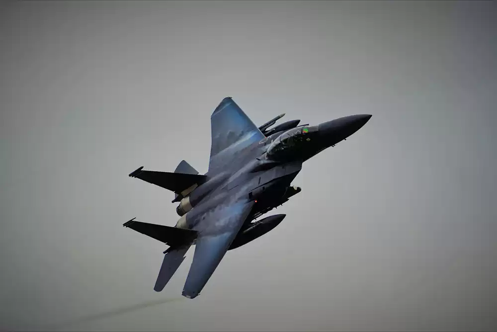 A bluish-gray fighter jet flying through the sky